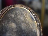 a close up of a silver clock with a face on it