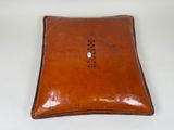 an image of a brown leather pillow with a button on it