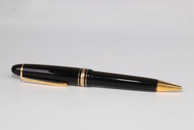 une image représentant un stylo noir et doré posé sur une surface blanche