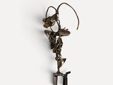 an image of a metal sculpture of a bird on a stand