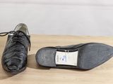 pair of black leather shoes with laces on a wooden table