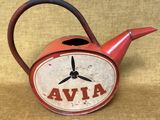 une vieille théière rouge ornée d'une horloge, posée sur une table