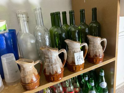 many bottles and pitchers on a shelf in a room