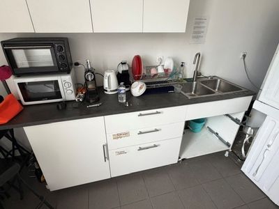 une petite cuisine équipée d'un micro-ondes, d'un réfrigérateur, d'un évier et d'un four à micro-ondes