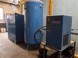 two air compressors in a room with a blue tank