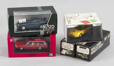 Trois petites voitures sont posées dans une boîte sur une surface blanche.