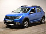 La Dacia bleue est garée dans un garage dont le sol est en damier.