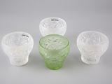 trois vases en verre vert posés les uns à côté des autres sur une surface blanche