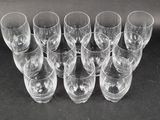 twelve empty wine glasses lined up in a row on a black surface
