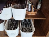 une étagère en bois sur laquelle sont posés des paniers contenant des couverts et des cuillères