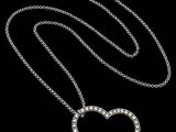 un pendentif en forme de cœur en diamant, suspendu à une chaîne, sur fond noir