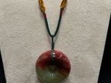 a close up of a necklace on a mannequin with a red, green and yellow bead