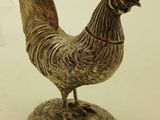a statue of a rooster on a pedestal on a white surface