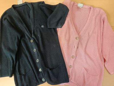 two sweaters that are on a hanger on the wall