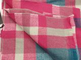 pink and blue checkered blanket on a table with a cell phone