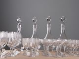 seven wine glasses and a decanter sitting on a table