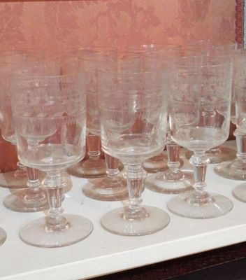 plusieurs verres à vin vides alignés sur une étagère devant un mur