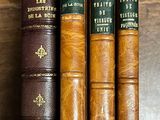 trois vieux livres posés sur une table en bois, dont l'un est marron et l'autre vert