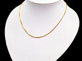 un collier en or autour du cou d'un mannequin, sur fond noir