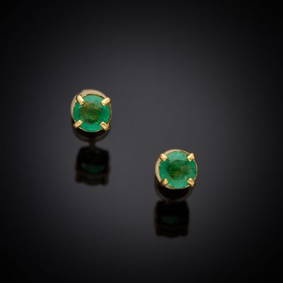 a pair of emerald earrings on a black surface