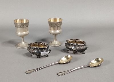 Plusieurs pièces d'argenterie sont disposées sur une table, parmi lesquelles des cuillères et des cuillères