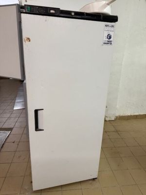 un réfrigérateur blanc posé au milieu d'un sol carrelé