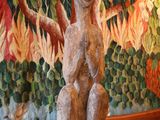 une statue représentant un homme assis sur une table devant un tableau