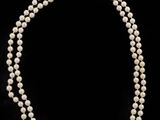 a single strand of pearl necklace on a black background