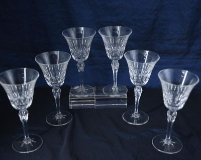 six verres à vin posés sur une table où se trouve une horloge