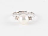 gros plan d'une bague en perles et diamants sur une surface blanche