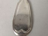 a silver spoon with a handle on a white surface