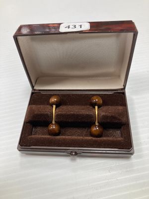 une paire de boutons de manchette en bois dans un coffret posé sur une surface blanche