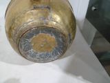 un vase en or posé sur une nappe blanche, sur une table