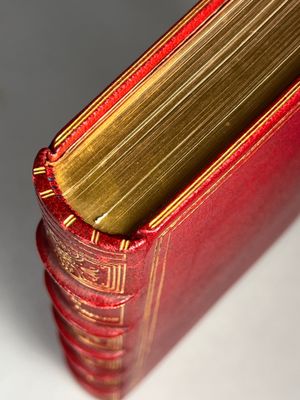 close up of a red book with gold binding on a white surface