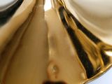 a close up of a gold lamp on a white table