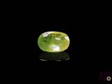 a close up of a green and white gemstone on a black surface