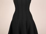 une robe noire posée sur un pied de mannequin, avec un mannequin blanc en arrière-plan