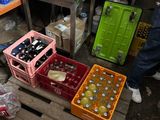 un homme debout à côté de caisses de sodas et de bière