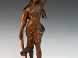 an antique bronze statue of a woman holding a snake on a pedestal