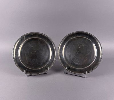 pair of silverplated dishes on stands on a grey background