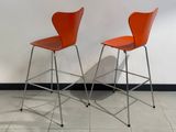 une paire de chaises orange posées contre un mur blanc dans une pièce