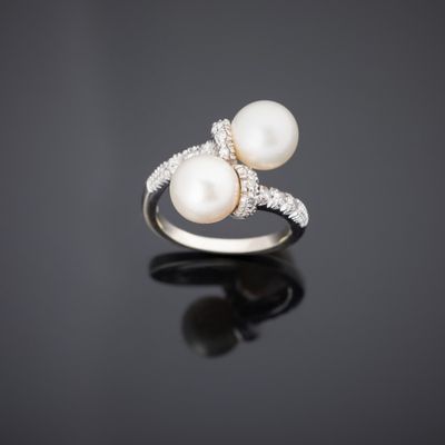 une bague en perles blanches et diamants sur une surface noire