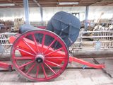 a horse drawn carriage with a red wheel in a barn