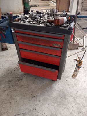 une boîte à outils rouge sur laquelle sont posés des outils, dans un garage
