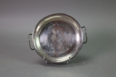 a silver plate on a stand on a gray surface