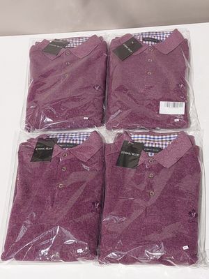four purple shirts are wrapped in plastic bags on a table
