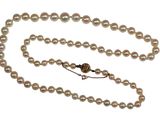 une photo d'un collier de perles blanches muni d'un fermoir en or