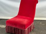 une chaise rouge ornée de franges, posée par terre