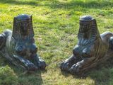 two statues of lions sitting on the grass in the park