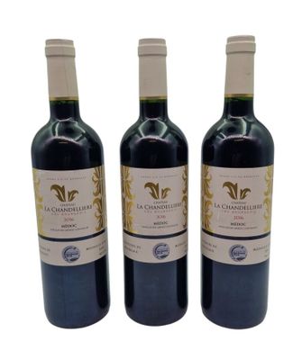 three bottles of red wine sitting next to each other on a white surface